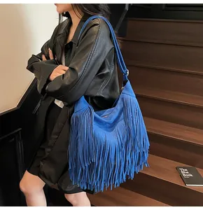 Detail of bright blue suede fringe hobo bag worn with a black leather jacket