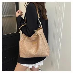 Detail of beige woven texture tote bag with gold chain strap and metal ring hardware