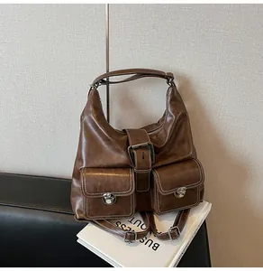Close-up of brown vintage shoulder bag with dual front pockets and white contrast stitching
