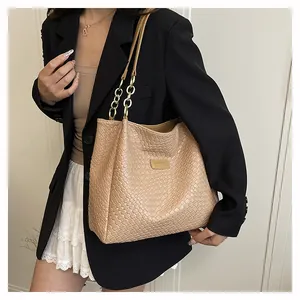 Detail of beige woven leather tote bag with fine texture and gold chain link handle