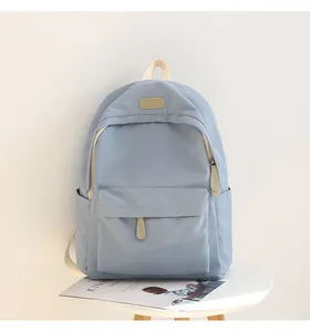 Detail shot of a light blue waterproof Oxford backpack with brown leather brand patch
