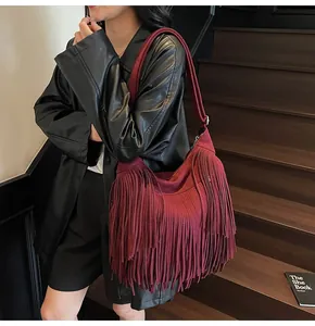 Detail of burgundy fringe hobo bag in matte suede style worn with black leather jacket