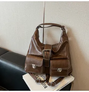 Detail of vintage brown leather tote bag featuring white stitching and silver buckles