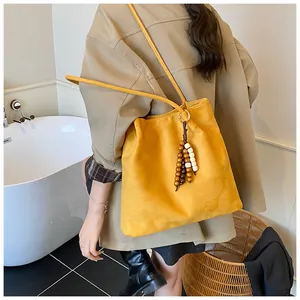 Detail of ginger suede tote bag with long shoulder straps and wooden bead charm accessory