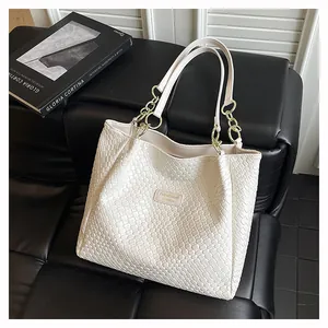 Macro detail of cream woven tote bag texture with elegant gold chain strap