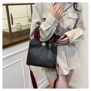 Nahaufnahme der Webstruktur und des Goldschlosses der schwarzen Tasche mit Riemen