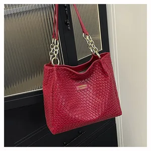 Close-up of red woven tote bag featuring gold chain straps and metal fashion plate