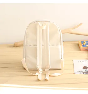 Detail of the back of a beige oxford backpack featuring wide straps and a trolley sleeve