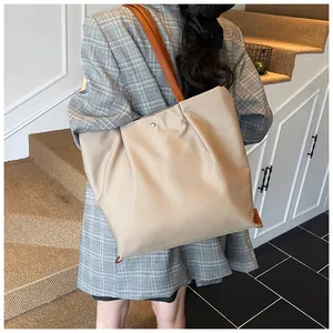 Detail van geplooide beige shopper met bruine banden, gedragen over de schouder in een scène