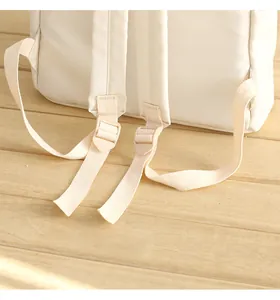 Detail view of adjustable shoulder straps and durable buckles on the cream Oxford backpack
