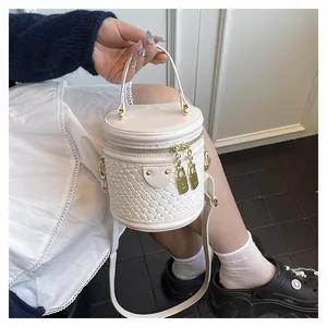 Detail einer beigen Beuteltasche mit Webstruktur, goldfarbenem Reißverschluss und Griff