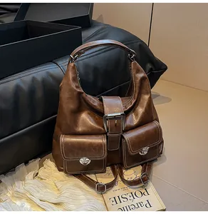 Detail of brown vintage leather tote with contrast stitching and metal buckles