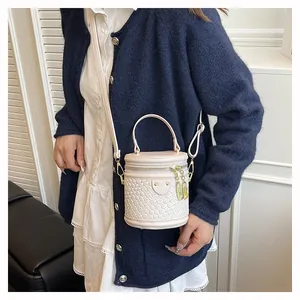 Detail der cremefarbenen Beuteltasche mit Webstruktur, goldener Hardware und Gurt