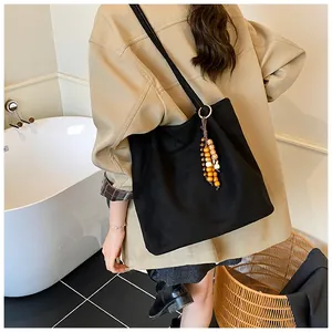Close-up of black suede tote bag featuring natural wood bead tassel detail