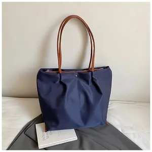 Grote marineblauwe geplooide shopper met bruine lederen handvatten en ritssluiting