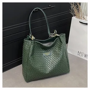Close-up of deep green woven tote bag with metallic logo and chain handle detail