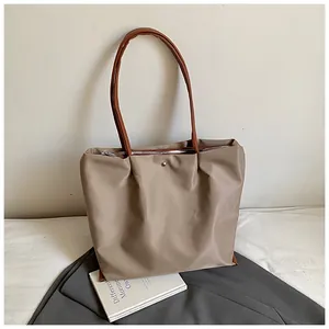 Detail van kaki geplooide shopper met zilveren rits en bruine slanke handvatten