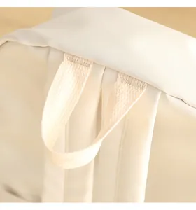 Reinforced stitching and durable top handle detail on a beige waterproof oxford backpack