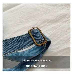 Close-up of adjustable denim shoulder strap with vintage bronze metal buckle on light blue bag