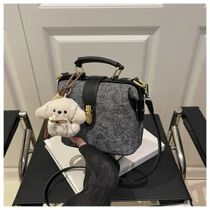 Detail of grey tweed doctor bag featuring gold metal clasp and plush puppy charm accessory