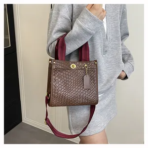 Braune Handtasche mit Krokostruktur, burgunderrotem Gurt und elegantem goldenem Drehverschluss
