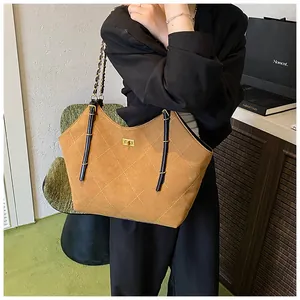 Detail of a brown quilted tote bag featuring white diamond stitching and golden turn-lock