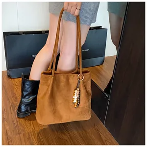 Detail of suede caramel tote bag featuring bohemian beaded charm and slim shoulder straps