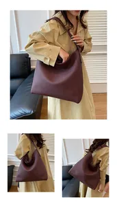 Detalle de un bolso tote burdeos de cuero suave que muestra gran capacidad y textura lisa