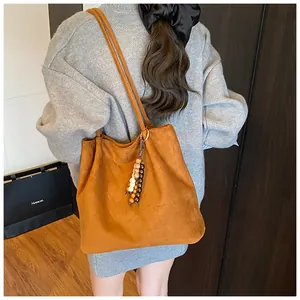 Detailed close-up of retro suede tote bag in caramel brown with decorative wooden beads