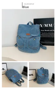 Detailed close-up of blue denim backpack with leather logo and metallic buckles
