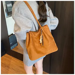 Detail of caramel suede tote bag featuring a decorative vintage wooden bead charm