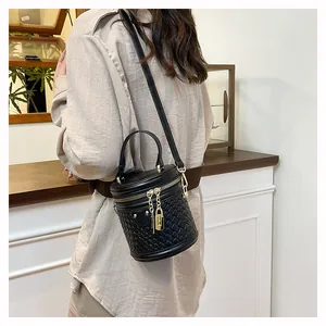 Detail der schwarzen geflochtenen Eimertasche mit goldenen Beschlägen an einem Model