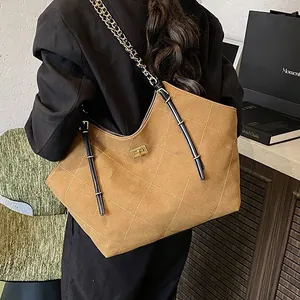 Brown quilted suede tote bag with chain strap and gold twist lock shown on shoulder