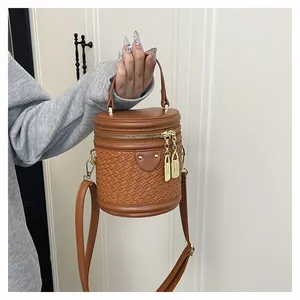 Detail der braunen Beuteltasche mit gewebter Ledertextur und goldenem Reißverschluss