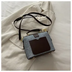 Detailed view of vintage blue denim bag with brown leather accents and gold hardware