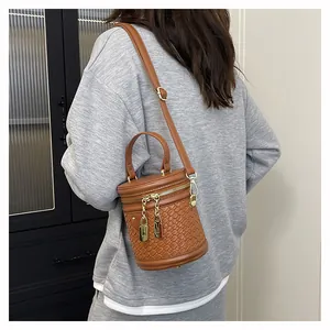 Schicke braune Beuteltasche mit Flechtmuster, getragen von einem Modell in Grau