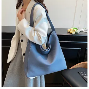 Detalle del bolso tote azul niebla que muestra la textura de cuero granulado y la correa suave