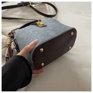Detailed bottom view of denim handbag with leather corners and gold protective studs