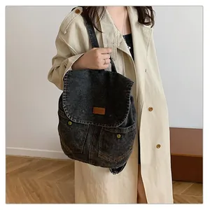 Detailed shot of dark grey denim backpack with flap cover and vintage brass metal buckles