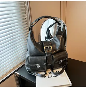 Detail of black wax leather tote bag with white stitching and metal buckle accents