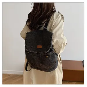 Detail of vintage grey denim backpack with leather patch and functional pockets