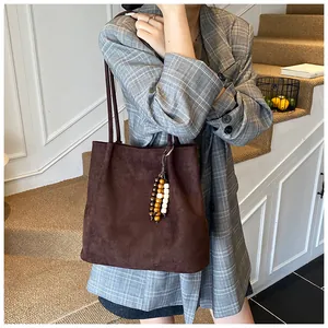Detail of dark brown suede tote bag featuring unique decorative wooden beads and slim straps