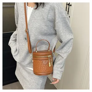Detail einer braunen Eimer-Tasche mit Webstruktur und glattem Ledergriff oben