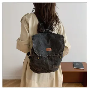 Detail of vintage black denim backpack featuring leather logo and metal button pockets