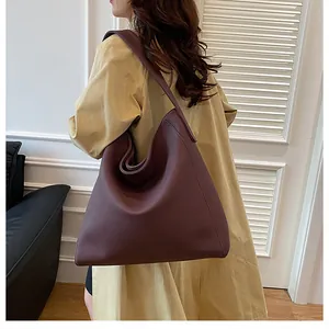 Vista lateral del bolso tote burdeos grande con correa ancha para el hombro en modelo