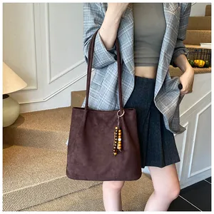 Close-up of a large brown suede tote bag with stylish wooden bead pendant detail