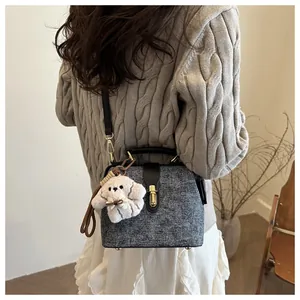 Detail of grey textured doctor bag featuring a plush puppy charm and golden metal clasp