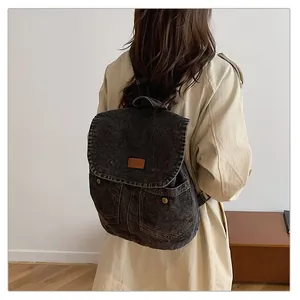 Macro shot showing the vintage dark gray denim texture and front pockets of the backpack