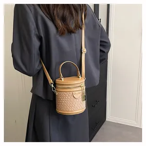 Detail der karamellfarbenen Eimertasche mit Webstruktur, goldener Hardware und Tragegriff
