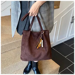 Detail of vintage brown suede tote bag with decorative multi-colored wooden bead charm